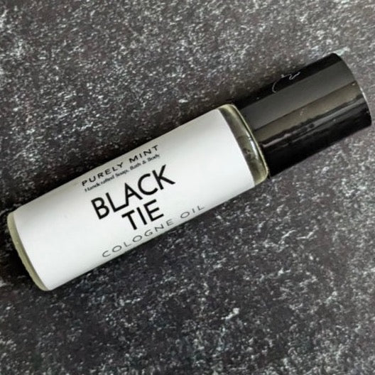 A roll-on cologne oil bottle with a white label that reads 'Black Tie Cologne Oil' and the brand 'Purely Mint'.