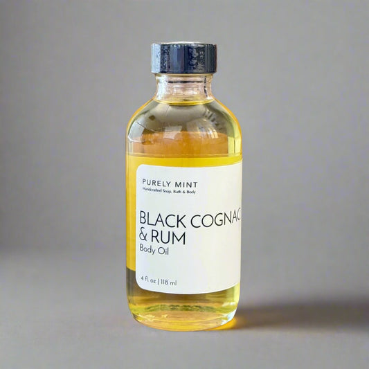 Black Cognac & Rum 4 oz body oil in clear class bottle white label bllack top. Commercial photography packshot, light gray seamless backdrop, neutral lighting