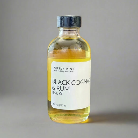 Black Cognac & Rum 4 oz body oil in clear class bottle white label bllack top. Commercial photography packshot, light gray seamless backdrop, neutral lighting