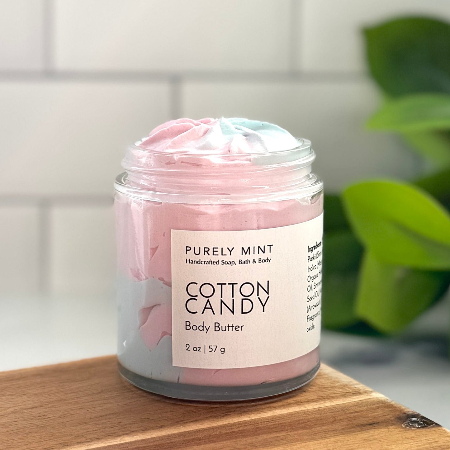 Cotton Candy pink and blue body butter, clear glass jar , white label, in a modern bathroom, marble, luxury, spa, plants, commercial advertising photography.