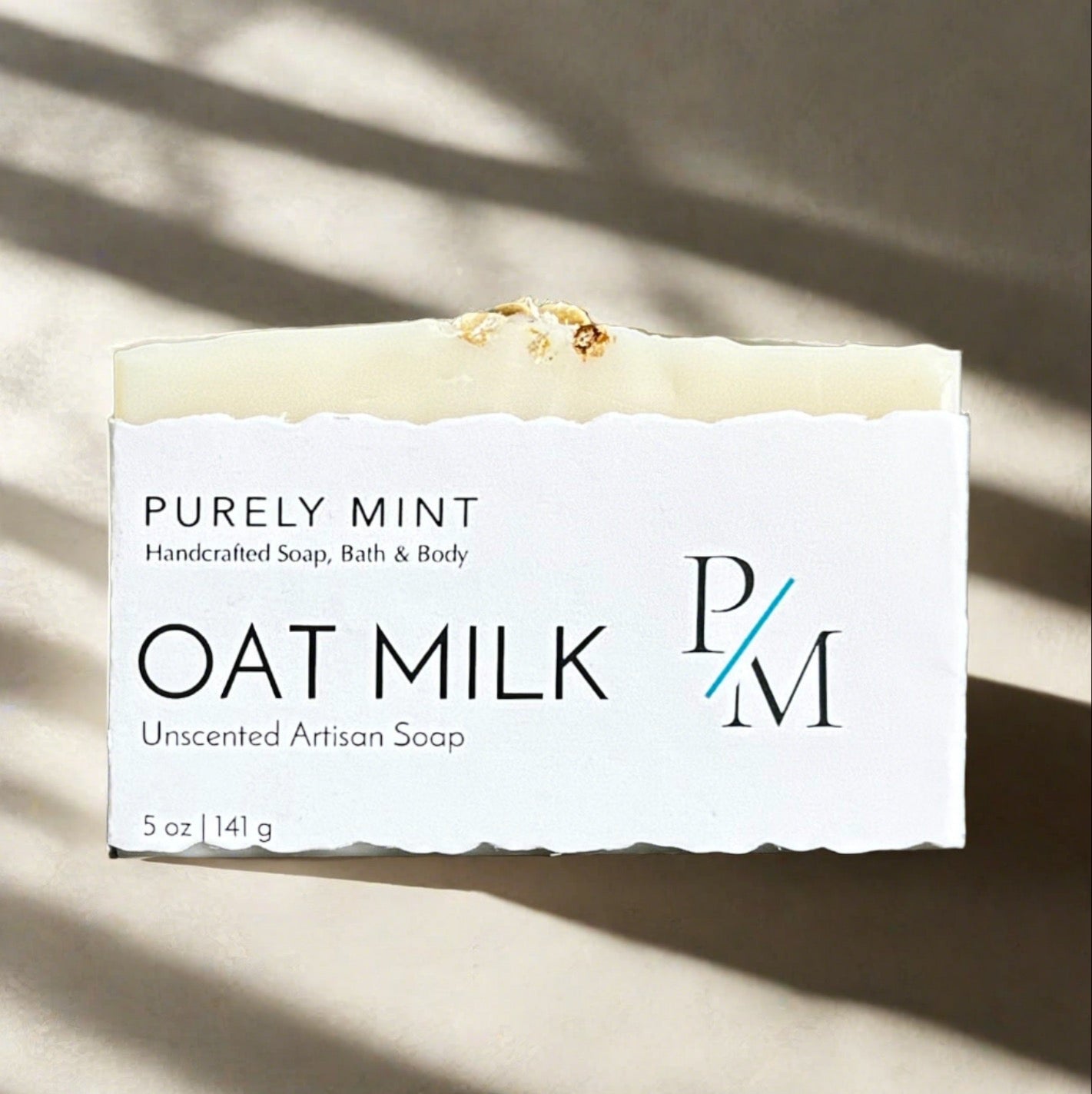 Oat Milk Unscented Soap wrapped in a white label on a neutral background