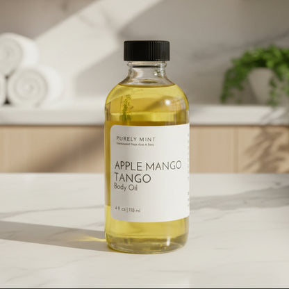Bottle of apple mango tango body oil in an advertising style shot, soft sun shadow, spa background, white marble counter, white rolled washcloths, green plant.