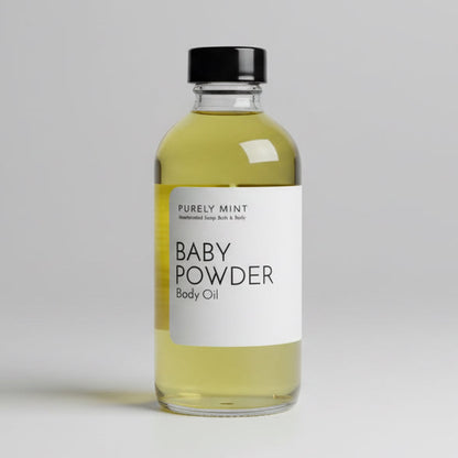 4 oz Baby Powder body oil in a glass bottle with bottle with a white label and black top. Light gray seamless backdrop, neutral lighting