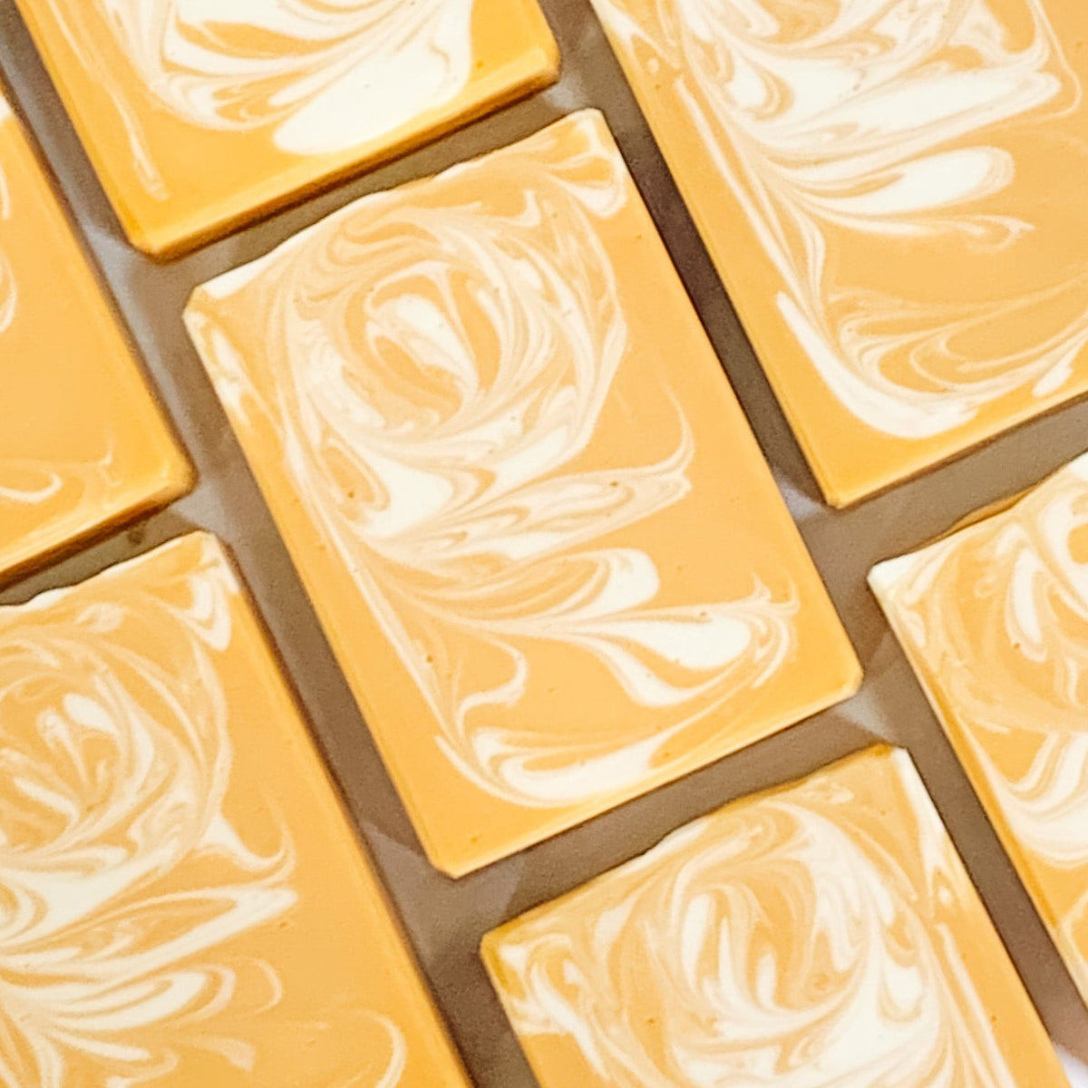 A grid of handmade banana coconut artisan soap bars with a marbled yellow and white pattern, arranged to form a larger image.