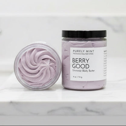 Two jars of 'Berry Good' shimmer body butter on a white marble counter.