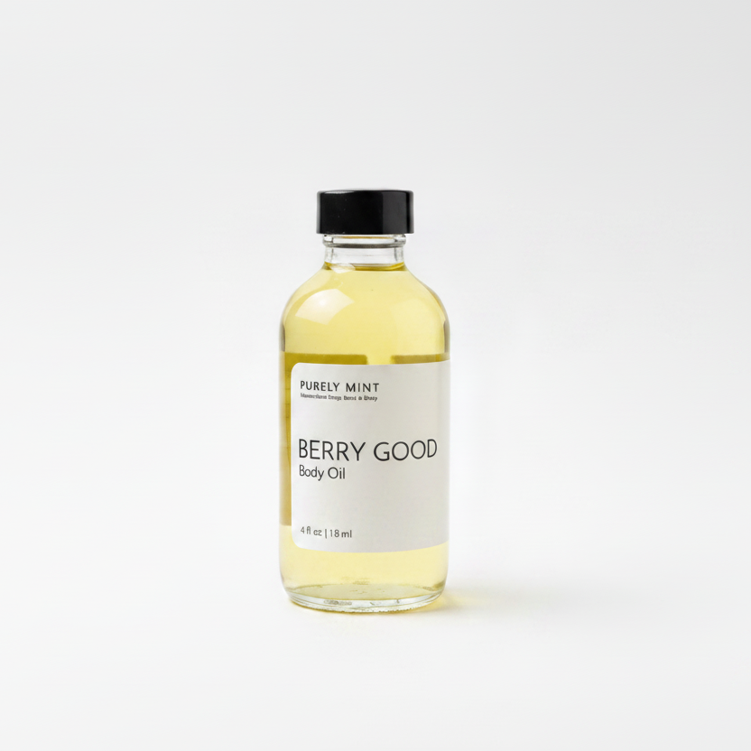 A bottle of Purely Mint Berry Good Body Oil with pale yellow oil inside, a white label, and a black cap, set against a plain white background.