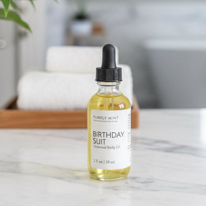 Birthday Suit Unscented Body Oil in a glass bottle with dropper on a marble counter.
