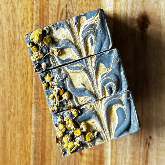 Black Chamomile Artisan Soap, handcrafted bars featuring charcoal and floral accents.