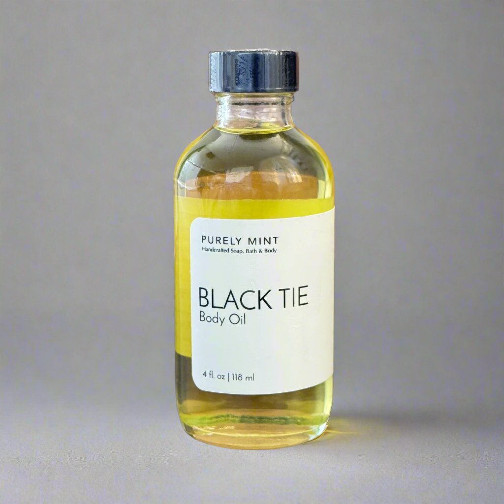 Black Tie 4 oz Body Oil in clear glass bottle, white label, black top,commercial photography packshot, light gray seamless backdrop, neutral lighting