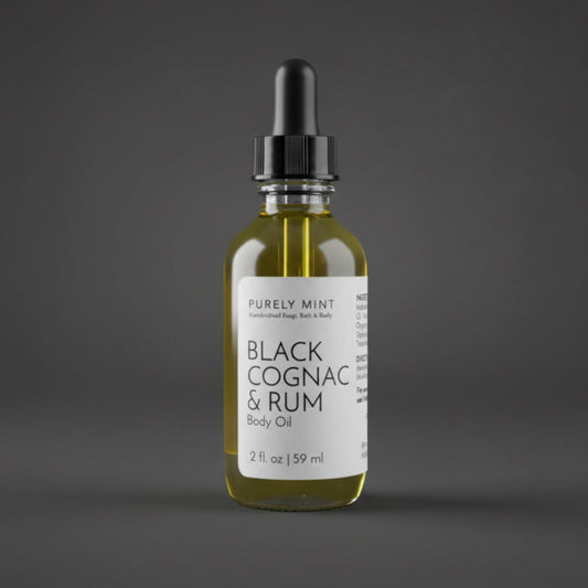 A 2 oz bottle of Black Cognac & Rum Body Oil with a white label and black dropper.