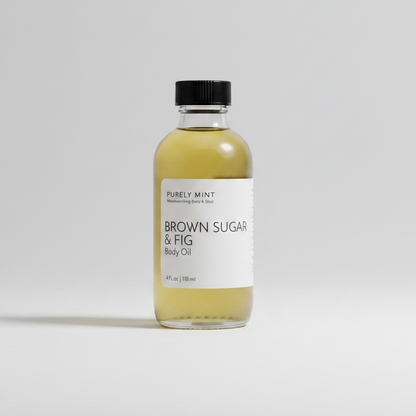 A clear glass bottle of Purely Mint Brown Sugar & Fig Body Oil with a black cap and white label, set against a clean light gray background.