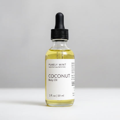 A 2 fl oz glass bottle of Purely Mint Coconut Body Oil with a black dropper cap, set against a neutral light gray background.