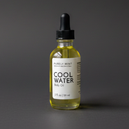 A bottle of Purely Mint Cool Water Body Oil with pale yellow oil inside, a white label, and a black dropper top, set against a dark gray backdrop.