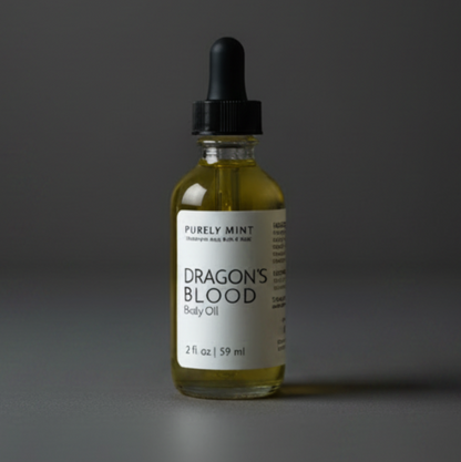 A small glass dropper bottle labeled 'Dragon's Blood' by Purely Mint filled with a yellow-body oil, set against a dark gray background.