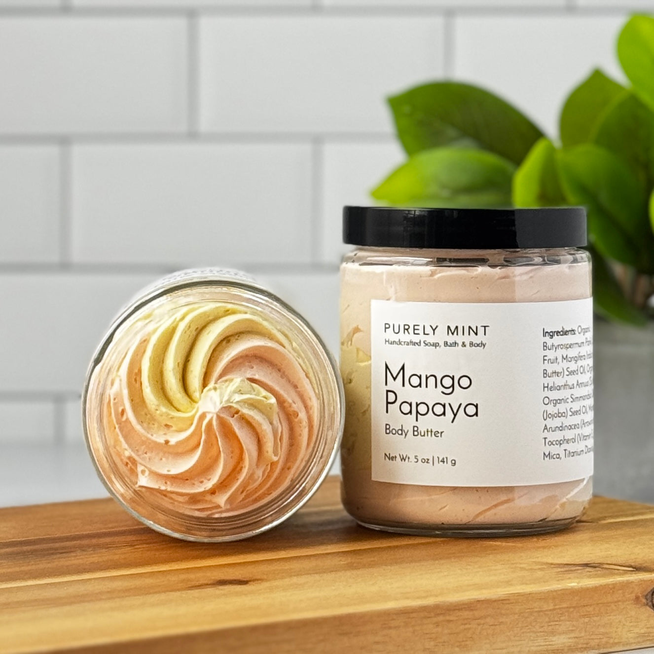 Jar of Mango Papaya body butter with a swirled texture on a wooden surface.