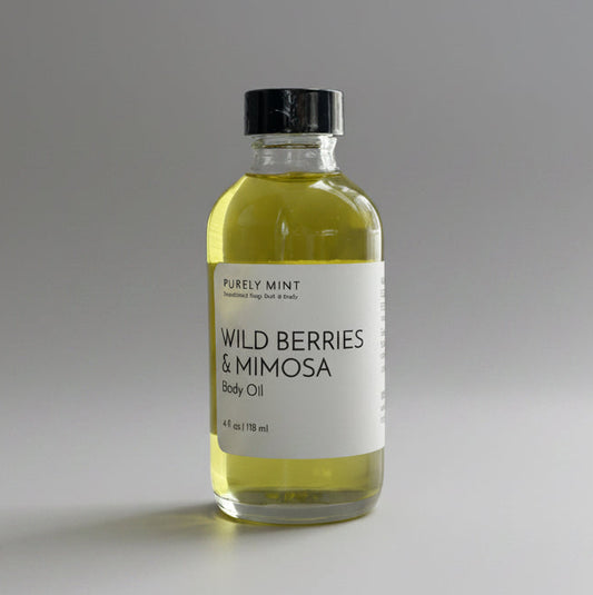 Bottle of Wild Berries & Mimosa body oil on a light gray backdrop.
