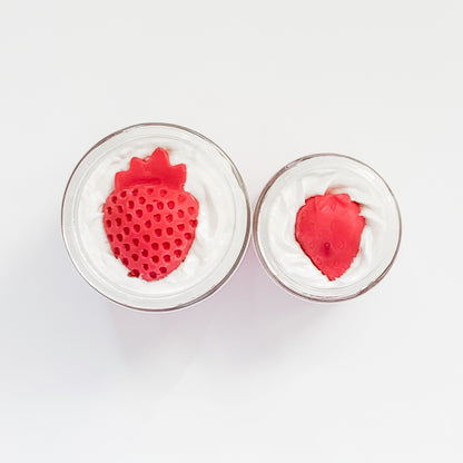 Two red strawberry-shaped objects in clear containers on a white background