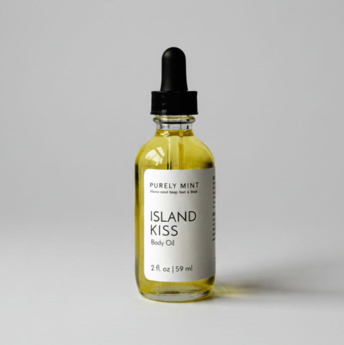A 2 fl. oz bottle of Purely Mint Island Kiss Body Oil with a black dropper cap, on a gray backdrop.