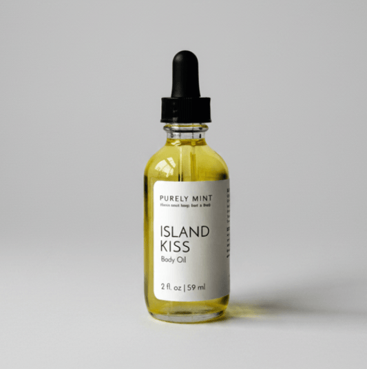 A 2 fl. oz bottle of Purely Mint Island Kiss Body Oil with a black dropper cap, on a gray backdrop.