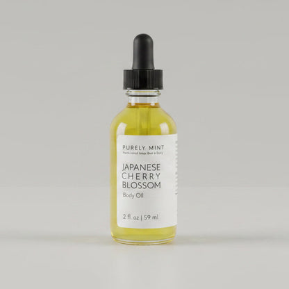 2 oz bottle of Japanese Cherry Blossom body oil with a dropper on a  light gray seamless backdrop.