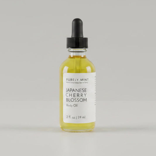 2 oz bottle of Japanese Cherry Blossom body oil with a dropper on a  light gray seamless backdrop.