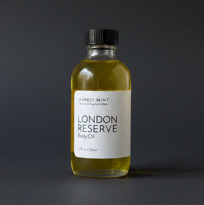 Bottle of London Reserve body oil on a dark gray surface with a neutral background