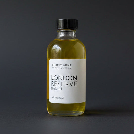Bottle of London Reserve body oil on a dark gray surface with a neutral background