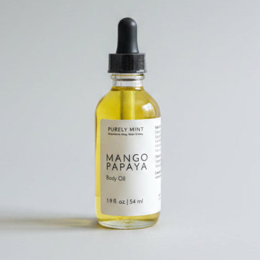 2 oz Mango Papaya body oil in a glass bottle with a dropper top on a light gray backdrop.