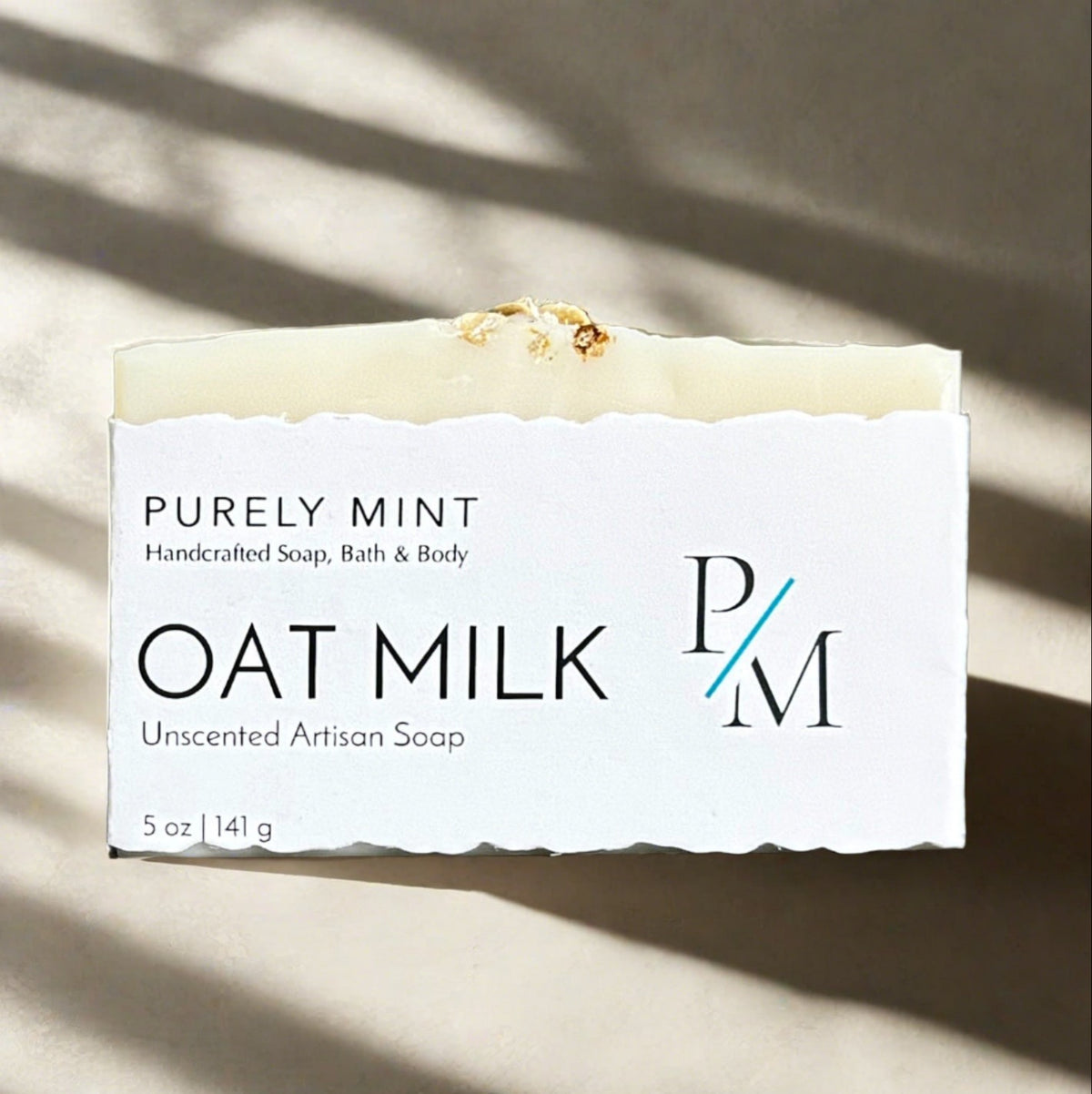 Oat Milk Unscented Soap wrapped in a white label on a neutral background