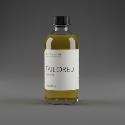 A bottle of Purely Mint Tailored Body Oil stands on a dark gray seamless backdrop.