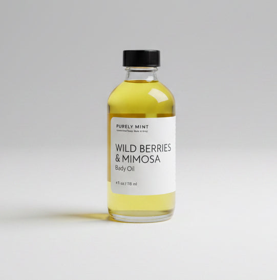 A bottle of  Wild Berries & Mimosa Body Oil stands on a neutral gray backdrop.