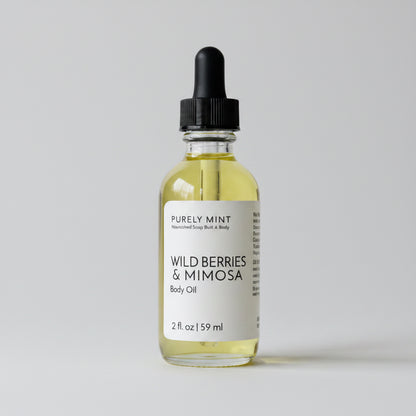 Bottle of Wild Berries & Mimosa body oil on a light gray background