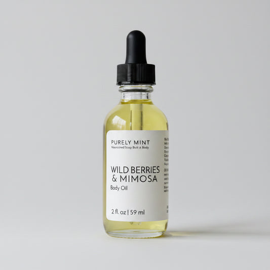 Bottle of Wild Berries & Minosa body oil on a light gray background