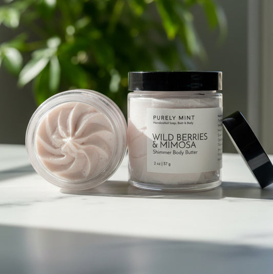 Jar of Purely Mint Wild Berries & Mimosa body butter on a marble counter with a plant in the background.
