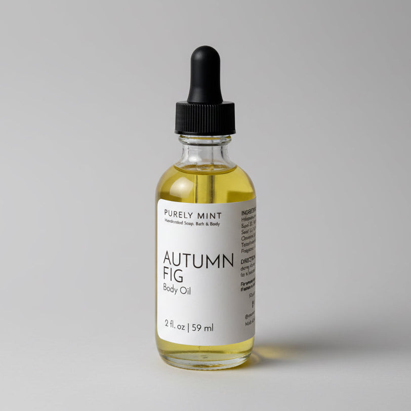 A 2 oz bottle of Autumn Fig Body Oil with a dropper top and a clean white label on a gray seamless backdrop, neutral lighting 