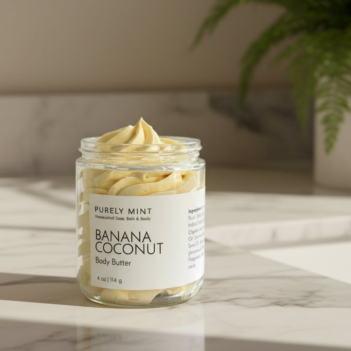 Jar of Banana Coconut yellow body butter with on a white marble counter with a green plant.