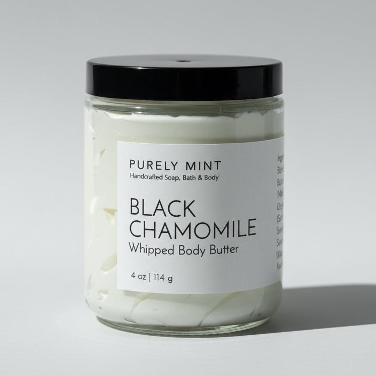 Jar of Black Chamomile whipped body butter with a black lid on a light grey backdrop..