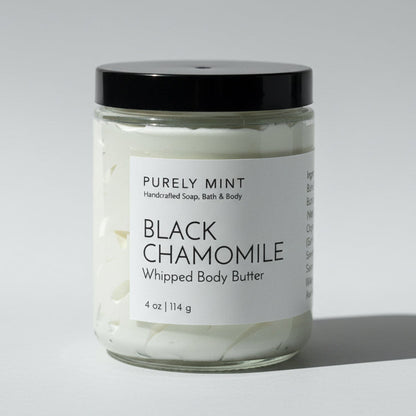 Jar of Black Chamomile whipped body butter with a black lid on a light grey backdrop..