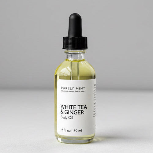 Bottle of White Tea & Ginger body oil on a marble surface with a gray background